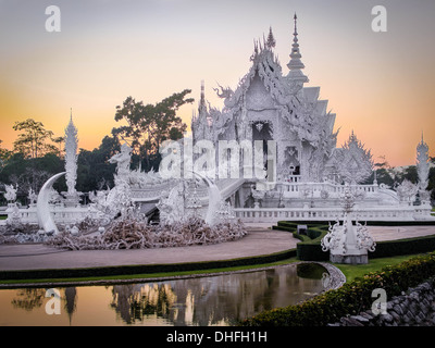 La splendida Wat Rong Khun, conosciuto popolarmente come il Tempio bianco, al tramonto in Chiang Rai, nel nord della Thailandia. Foto Stock