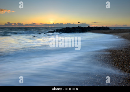 Le onde di colpire la spiaggia su Hurst allo spiedo, Milford-on-Sea, Hampshire al tramonto Foto Stock