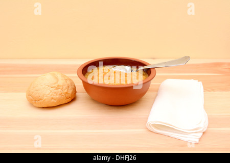 Versare in una ciotola di zuppa di lenticchie con pane e tovagliolo bianco Foto Stock