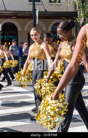 Buchholz High School marching band majorettes in giallo e nero costumi con oro pom pom, UF 2013 Homecoming Parade. Stati Uniti d'America Foto Stock