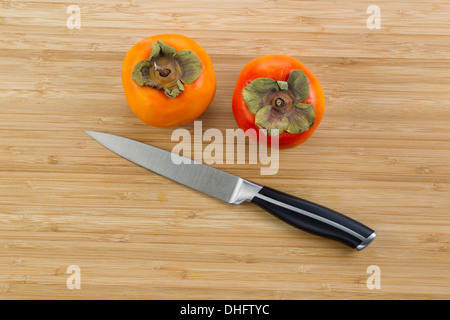 Foto orizzontale di secco fresche Cachi con singolo coltello giacente su di bamboo naturale il legno Foto Stock