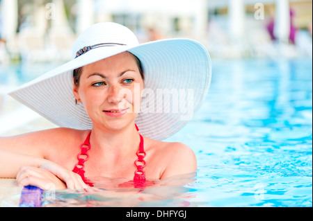 Giovane donna rilassandosi nella piscina del resort Foto Stock