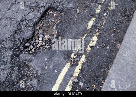 Buca strada danneggiata su London Road strada di guida Foto Stock