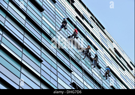 Cinque window cleaners il lavaggio di un edificio per uffici Foto Stock