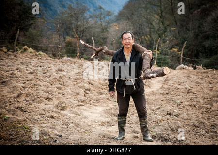 Un agricoltore bhutanesi portando alcuni di legna da ardere Foto Stock