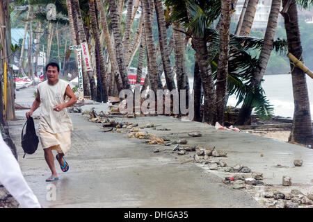 Il Boracay, Filippine - 8 Novembre 2013: un uomo che corre dal mare come Super Typhoon Haiyan slam nella costa est invio di palme, metallo e rocce attraverso l'aria Foto Stock