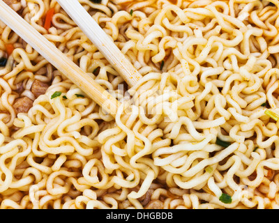Mangiare cucinato tagliatelle istante da bacchette di legno vicino fino Foto Stock