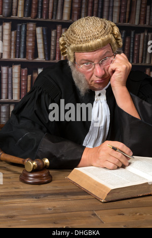 Annoiato giudice con autentica corte parrucca e martello in tribunale Foto Stock