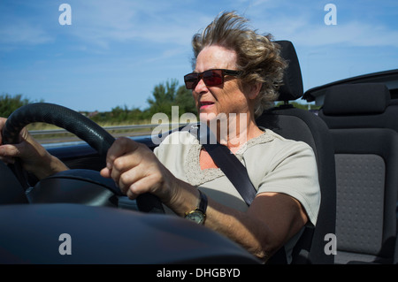 Senior Lady guidando il suo aperto cabriolet auto in una giornata di sole Foto Stock
