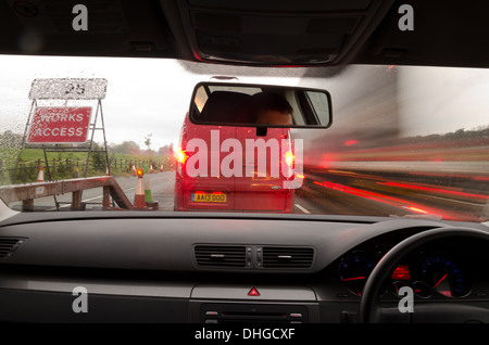 Vista attraverso il parabrezza di una vettura in movimento con motion blur e diverse sezioni sull'autostrada con opere stradali Automobili Autocarri Foto Stock