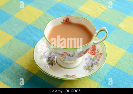 A cup of milk tea on a chequered tablecloth. Foto Stock