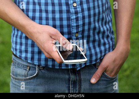 Un giovane uomo è utilizzando uno smartphone per ribaltamento con le sue dita Foto Stock