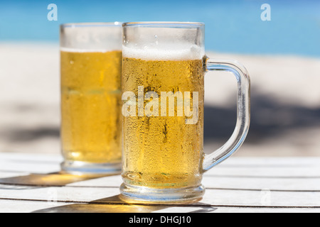 Due bicchieri di birra su di una spiaggia Foto Stock