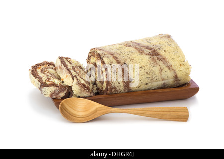Torta di noci in spugna rotolo in una lastra di legno isolato su sfondo bianco Foto Stock