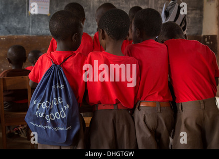Quattro ragazzi della scuola per una scrivania in un aula keniota uno con una borsa con il logo ' riciclaggio per la buona ' Foto Stock