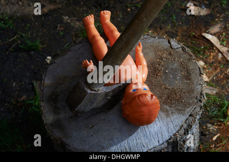 Esecuzione - omicidio del bambino di plastica giocattolo baby doll con un'ascia Foto Stock