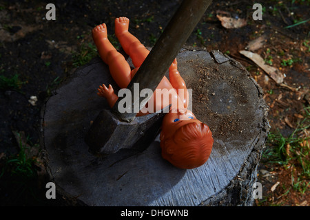 Esecuzione - omicidio del bambino di plastica giocattolo baby doll con un'ascia Foto Stock