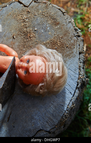 Esecuzione - omicidio del bambino di plastica giocattolo baby doll con un'ascia Foto Stock