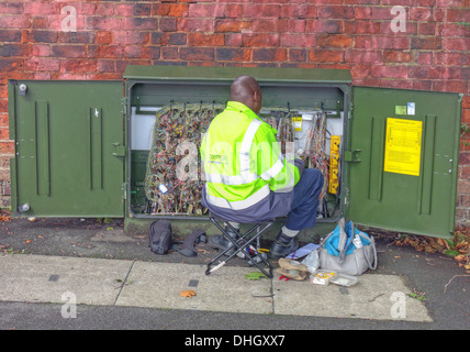 BT OpenReach ingegnere telecomunicazioni, riparazione guasto, in verde scatola armadio stradale, Walsall, West Midlands, Inghilterra, Regno Unito Foto Stock