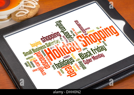 Vacanze shopping word cloud su una tavoletta digitale con una tazza di tè e cookie Foto Stock