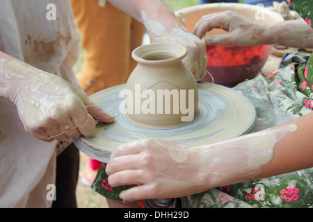 Le mani di due persone creare vaso sul tornio del vasaio. Insegnamento mestieri tradizionali. Foto Stock