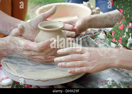 Le mani di due persone creare vaso sul tornio del vasaio. Insegnamento mestieri tradizionali. Foto Stock