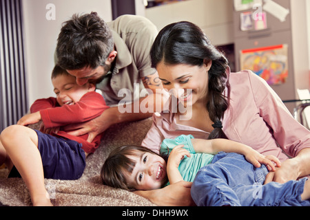 Famiglia con due bambini che giocano sul divano Foto Stock