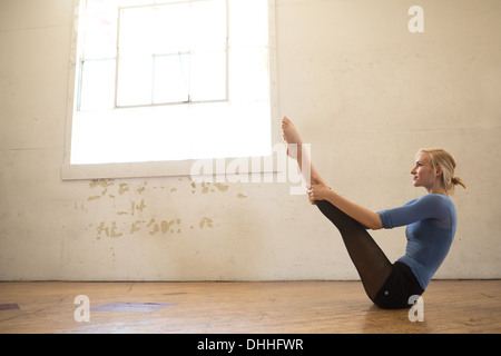 Ballerino femmina seduto sul pavimento con le gambe sollevate Foto Stock