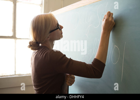 Insegnante scrivere sulla lavagna con Chalk Foto Stock