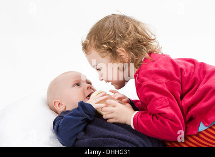 Carina ragazza che gioca con il suo fratellino in sfondo grigio chiaro. Studio shot Foto Stock