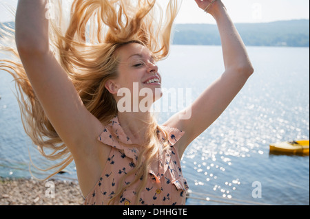 Ritratto di giovane donna con capelli lunghi biondi e a braccia alzate Foto Stock