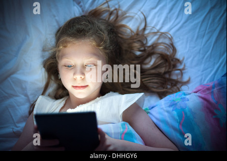 Ragazza nel letto tramite un computer tablet ipad Foto Stock