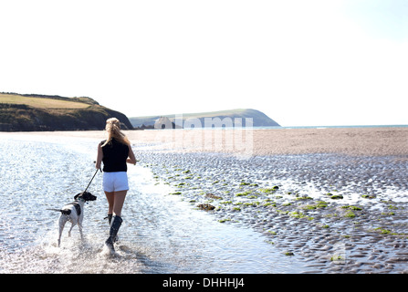 Donna cane a camminare sulla spiaggia, Wales, Regno Unito Foto Stock