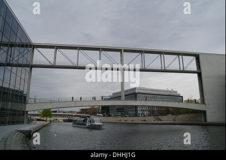 Cielo grigio vista chiatta turistico passando sotto ponti pedonali tra Paul Lobe Haus e Elisabeth Luders Haus, il fiume Sprea, Berlino Foto Stock