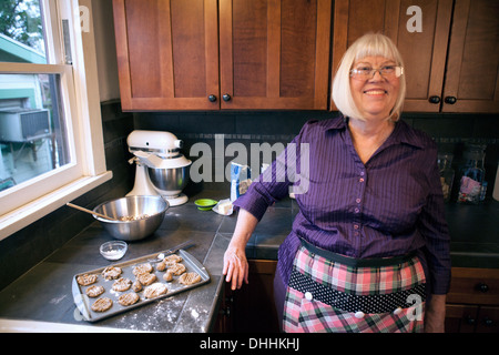 Senior woman standing in cucina con il vassoio di biscotti fatti in casa Foto Stock