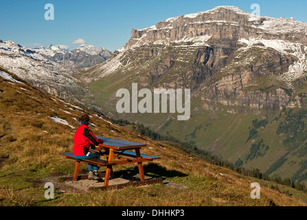 Walker guardando da una zona di riposo in alto sopra il Urnerboden alta valle del Klausen Pass, Urnerboden, Cantone di Uri Foto Stock