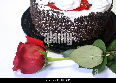 Una rosa rossa e una fetta di torta. Foto Stock