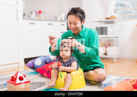 Il padre del bambino di taglio di capelli sul pavimento Foto Stock