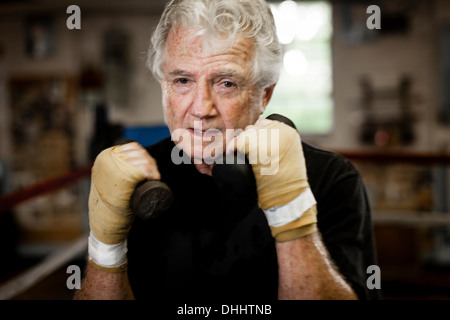 Senior uomo indossando i guanti, sollevamento pesi Foto Stock