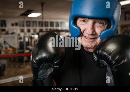 Senior uomo che indossa guantoni da pugilato e casco Foto Stock