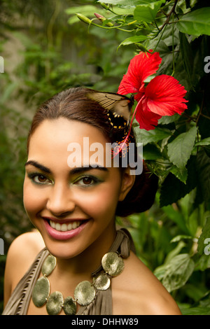 Ritratto di giovane donna con orchidea rossa e fogliame Foto Stock