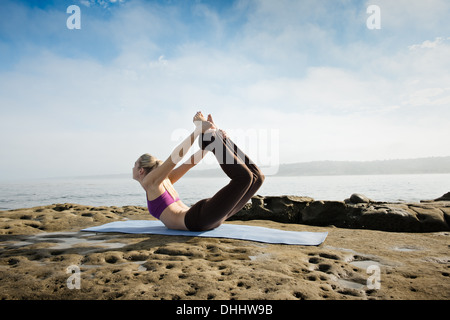 Donna fare yoga a costa Foto Stock