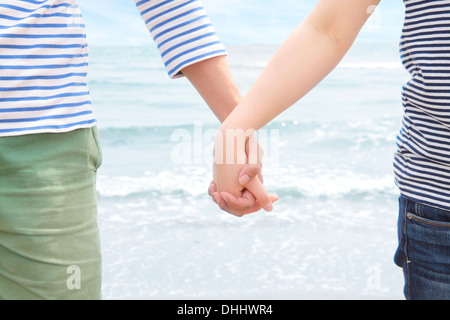 Coppia giovane tenendo le mani nella parte anteriore di mare Foto Stock