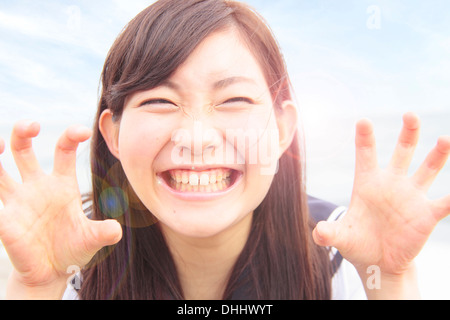 Giovane donna tirando divertente il viso e le mani come artigli Foto Stock