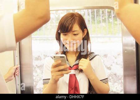 Giovane donna in piedi sul treno utilizza lo smartphone Foto Stock