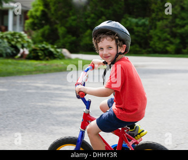 Ritratto di giovane ragazzo in bicicletta equitazione sul viale di accesso Foto Stock