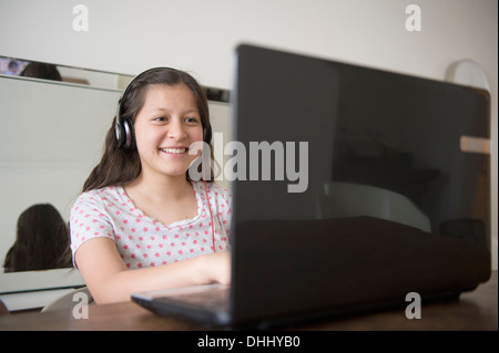 Ragazza adolescente che indossano le cuffie utilizzando laptop Foto Stock