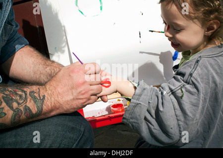Padre pittura forma di cuore sulla figlia la mano Foto Stock