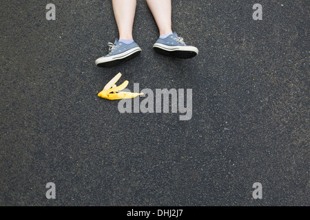 Coppia di gambe e buccia di banana su asfalto Foto Stock