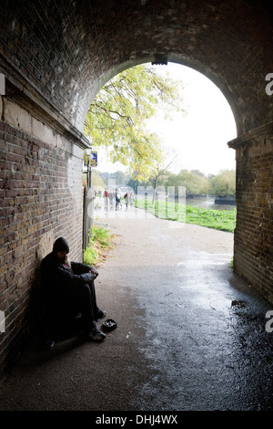 Un senzatetto di accattonaggio a Londra sotto il ponte sul percorso del Tamigi a Richmond, London REGNO UNITO Foto Stock